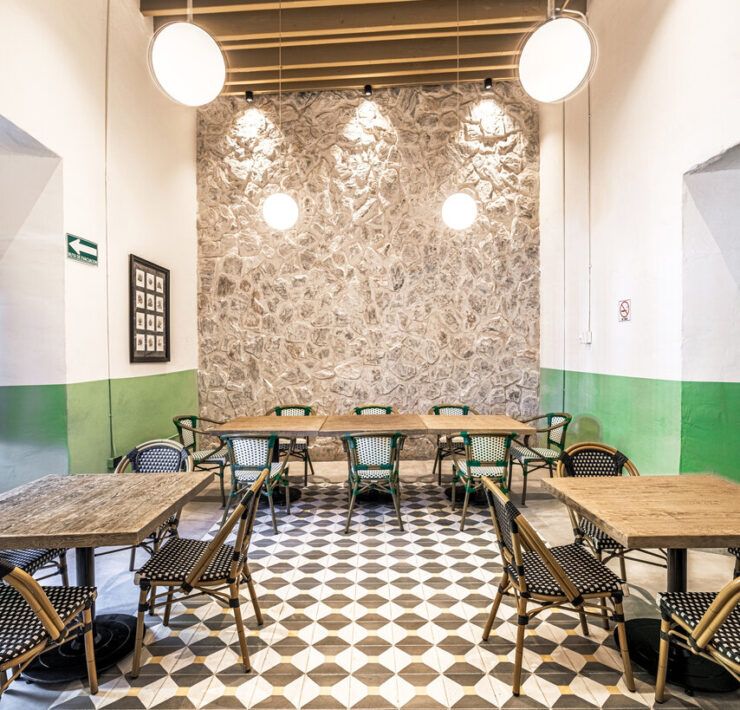 Salón interior de Casona Obregón 55 con muro de piedra original y mobiliario contemporáneo"