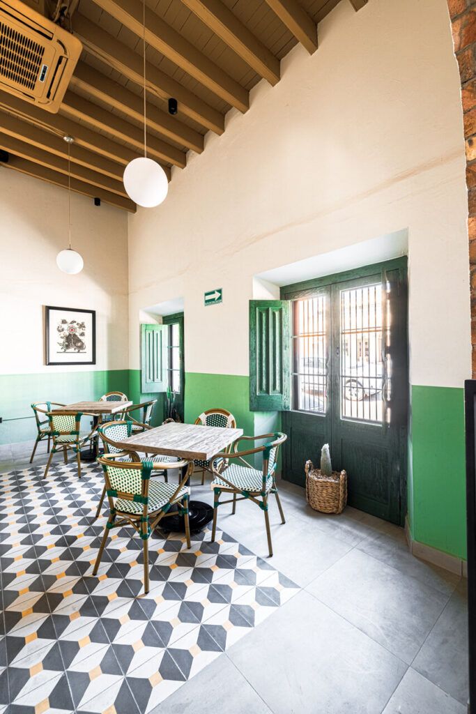 Salón de Casona Obregón 55 con paredes verdes y mesas de madera.