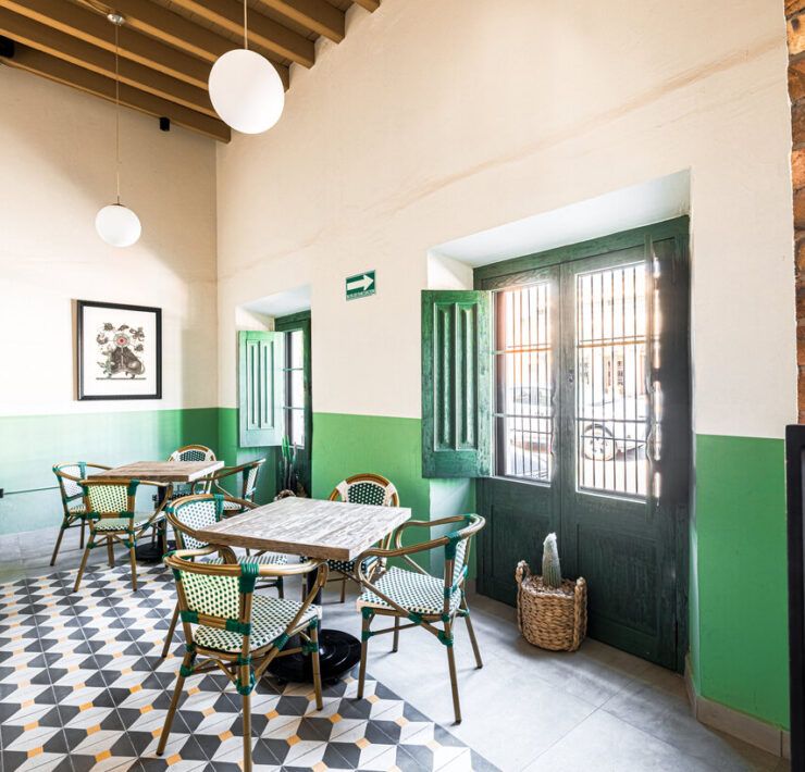 Salón con paredes verdes y mesas de madera en Casona Obregón 55