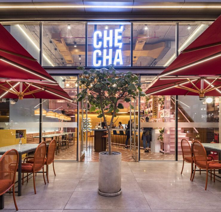 Entrada de Checha Tea Bar & Food Station, un restaurante tematico en LIma de Lee Arquitectos, con letrero de neón y toldos rojos