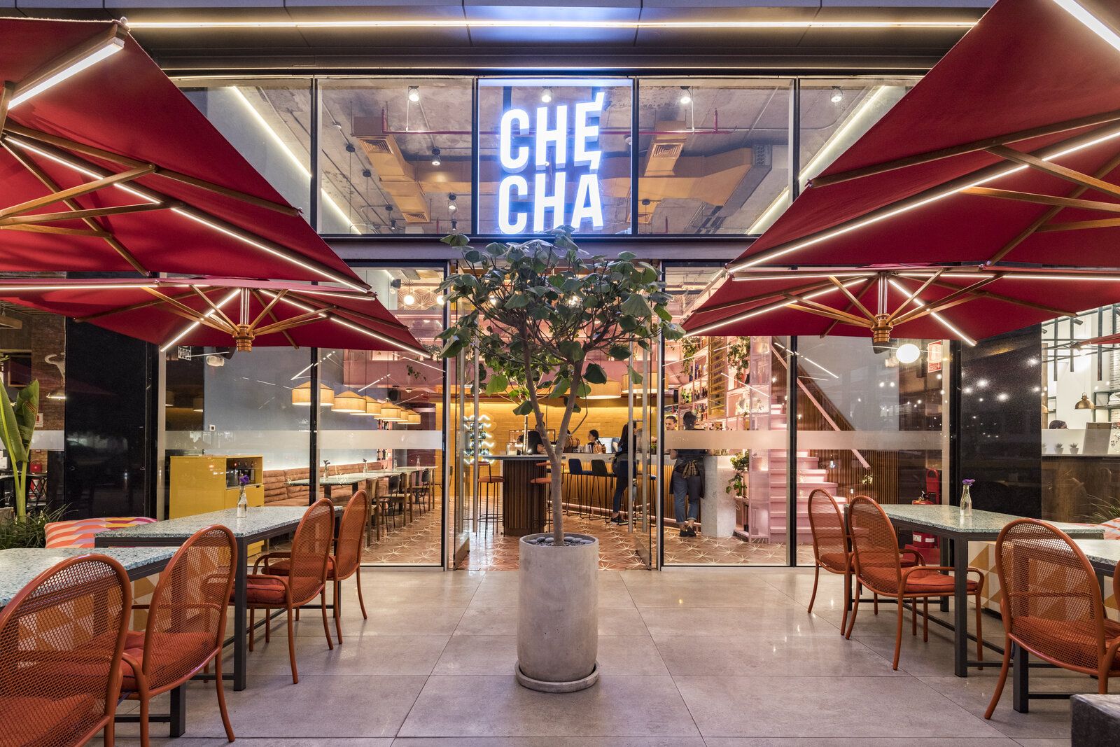 Entrada de Checha Tea Bar & Food Station, un restaurante tematico en LIma de Lee Arquitectos, con letrero de neón y toldos rojos
